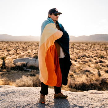 person wearing multicolored blanket in the desert