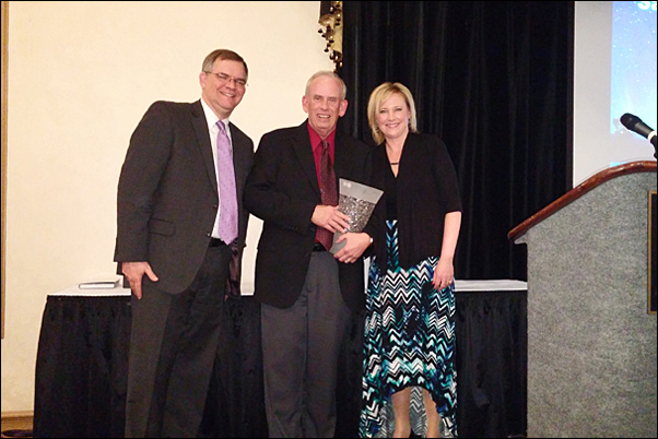 David Bywater, MAS, CEO of Bankers Advertising (left) and Erica Kelley-Gogel, CAS, the distributor's vice, present Tim Chamberlain with the Sales Person of the Year. 